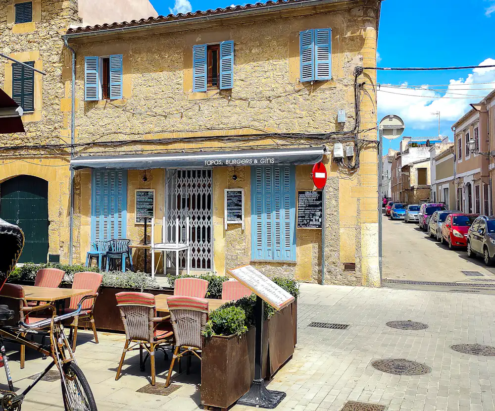 Café en terrasse, maison de pierre aux volets bleus.